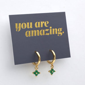 Gold hoop earrings with green gemstones on a card that says 'you are amazing' on a white background
