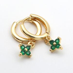 Gold hoop earrings with green gemstone charms on a white background