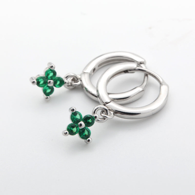 Silver earrings with green gemstones on a white background