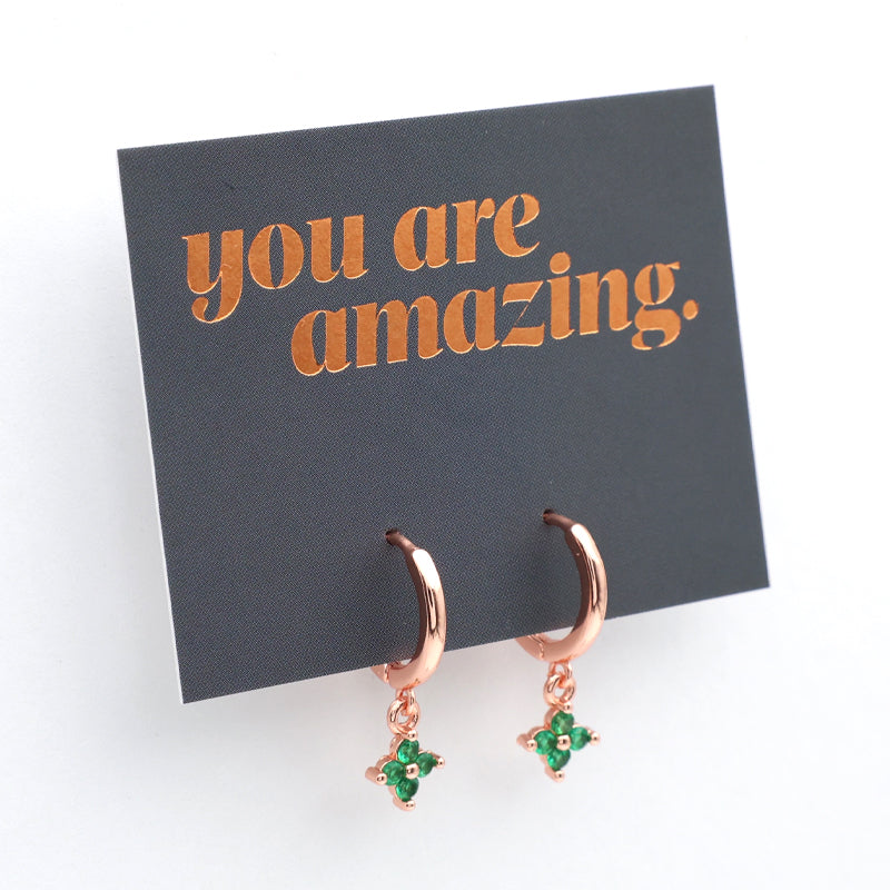 Rose gold earrings with green gemstones on a card that says 'you are amazing'.