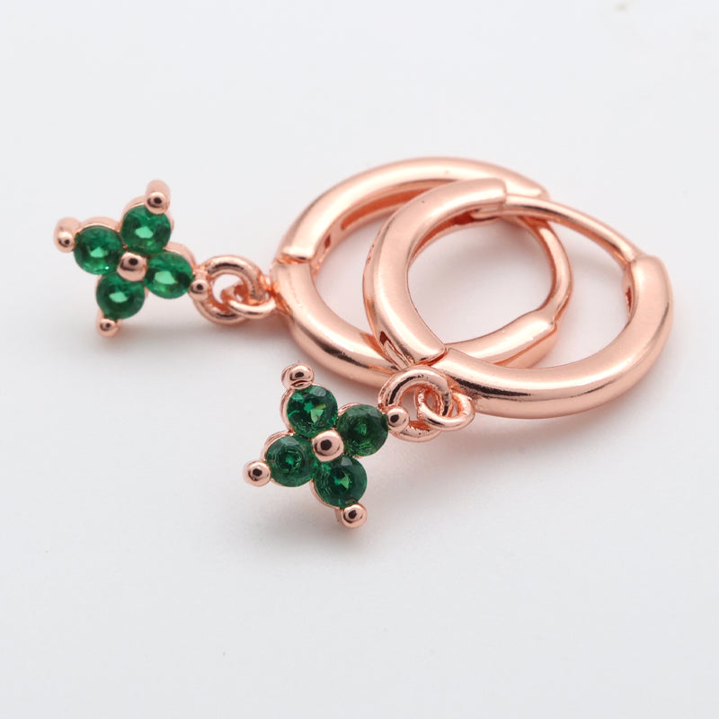 Rose gold hoop earrings with green gemstone clover charms on a white background