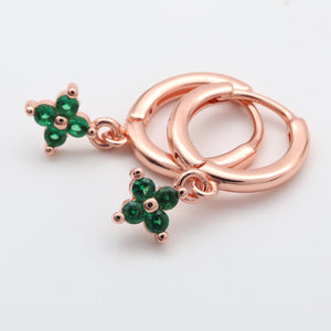 Rose gold hoop earrings with green gemstone clover charms on a white background