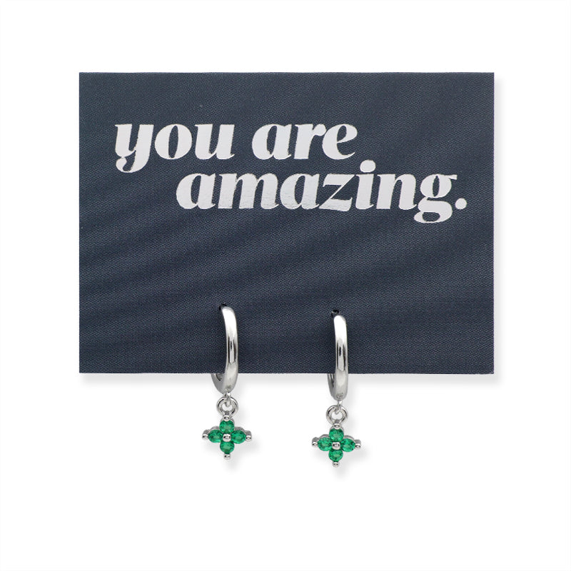 Silver earrings with green stones on a card that says 'you are amazing'.