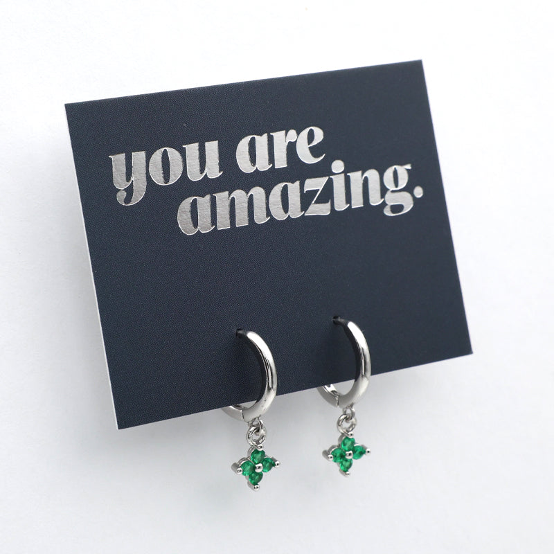 Silver earrings with green gemstones on a card that says 'you are amazing' on a white background