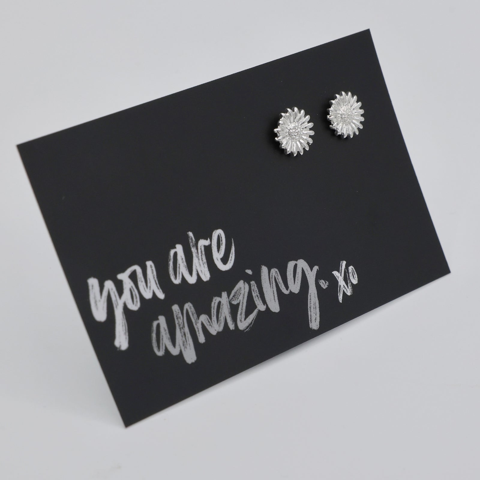 Silver sunflower earrings on a black card with 'you are amazing' text