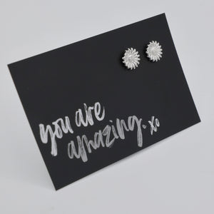 Silver floral earrings on a black card with 'you are amazing xo' text.