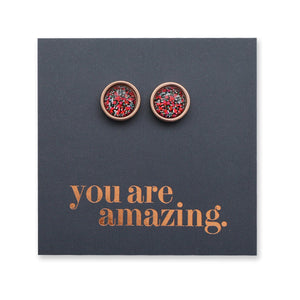 Pair of round earrings with red and gold design on a dark blue card with 'you are amazing' text.