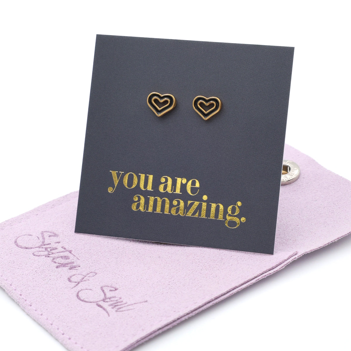 Heart-shaped earrings on a card with 'you are amazing' text, placed on a purple cloth.