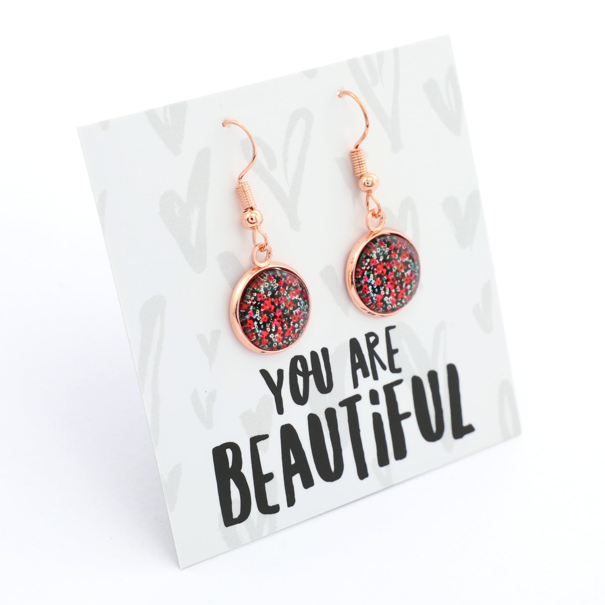 Earrings with glittery pink and red stones on a card with 'You are Beautiful' text.
