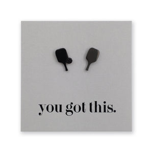 A square gray plaque or sign with two small pickleball paddle-shaped stud mounted near the top and the phrase 'you got this.' printed in black lowercase serif text near the bottom, shown on a white background.