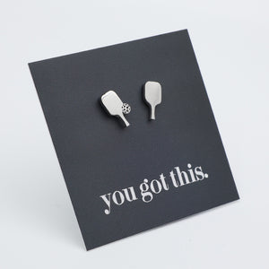 A pair of silver pickle ball paddle-shaped-shaped stud earrings displayed on a dark gray square card that reads 'you got this.' in white script, photographed on a light gray background.