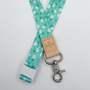 Aqua Daisies lanyard with white flowers, a tan So Loved tab, silver-tone clasp and white breakaway fastening.