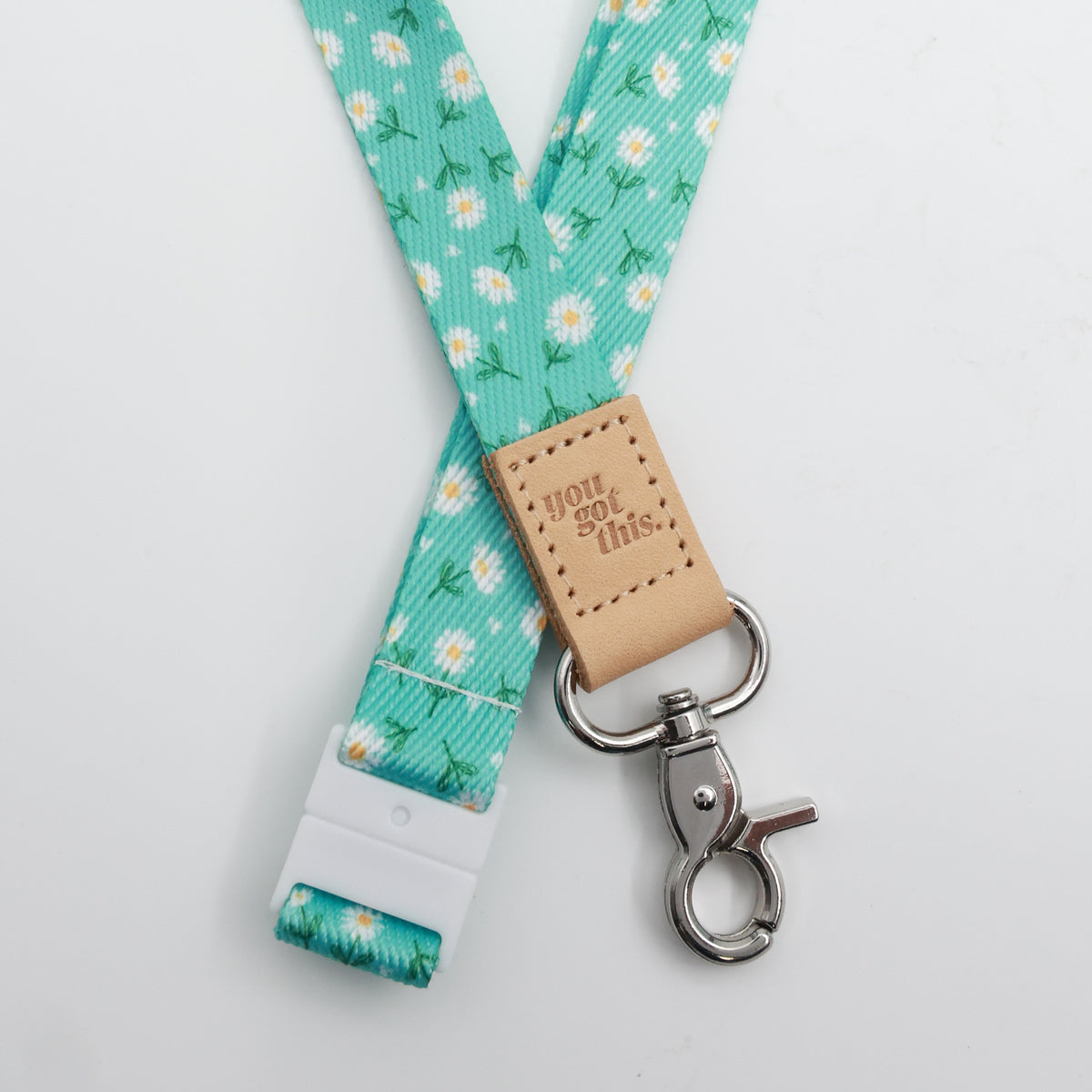 Aqua Daisies lanyard with white flowers, a tan You Got This tab, silver-tone clasp and white breakaway fastening.