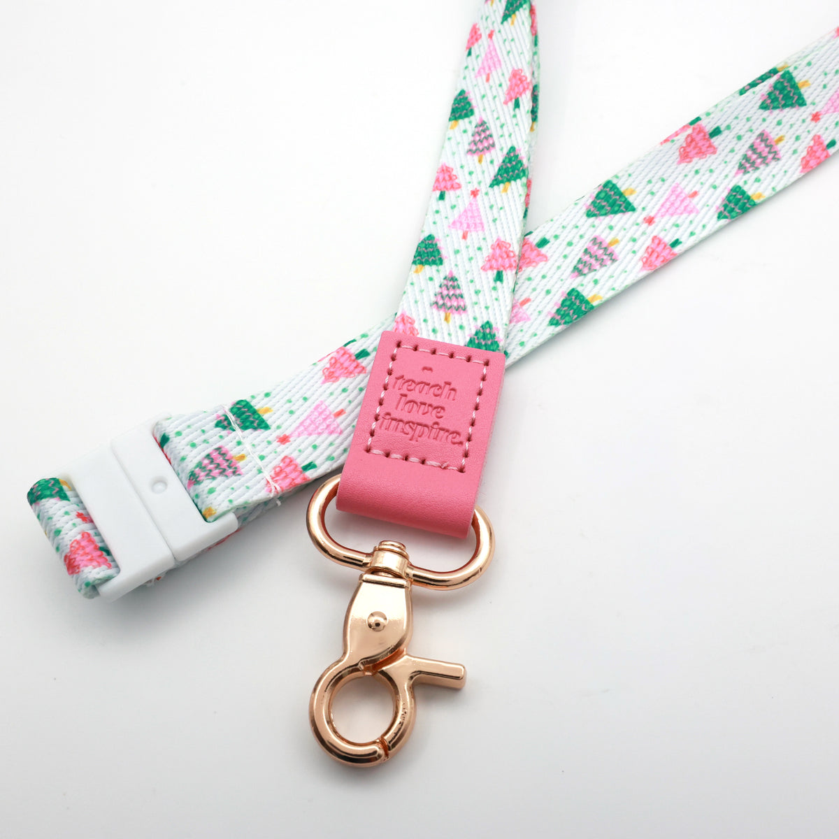 Close-up of the Christmas Delight lanyard with a pink Teach Love Inspire tab, colourful Christmas tree print and gold-tone clasp.