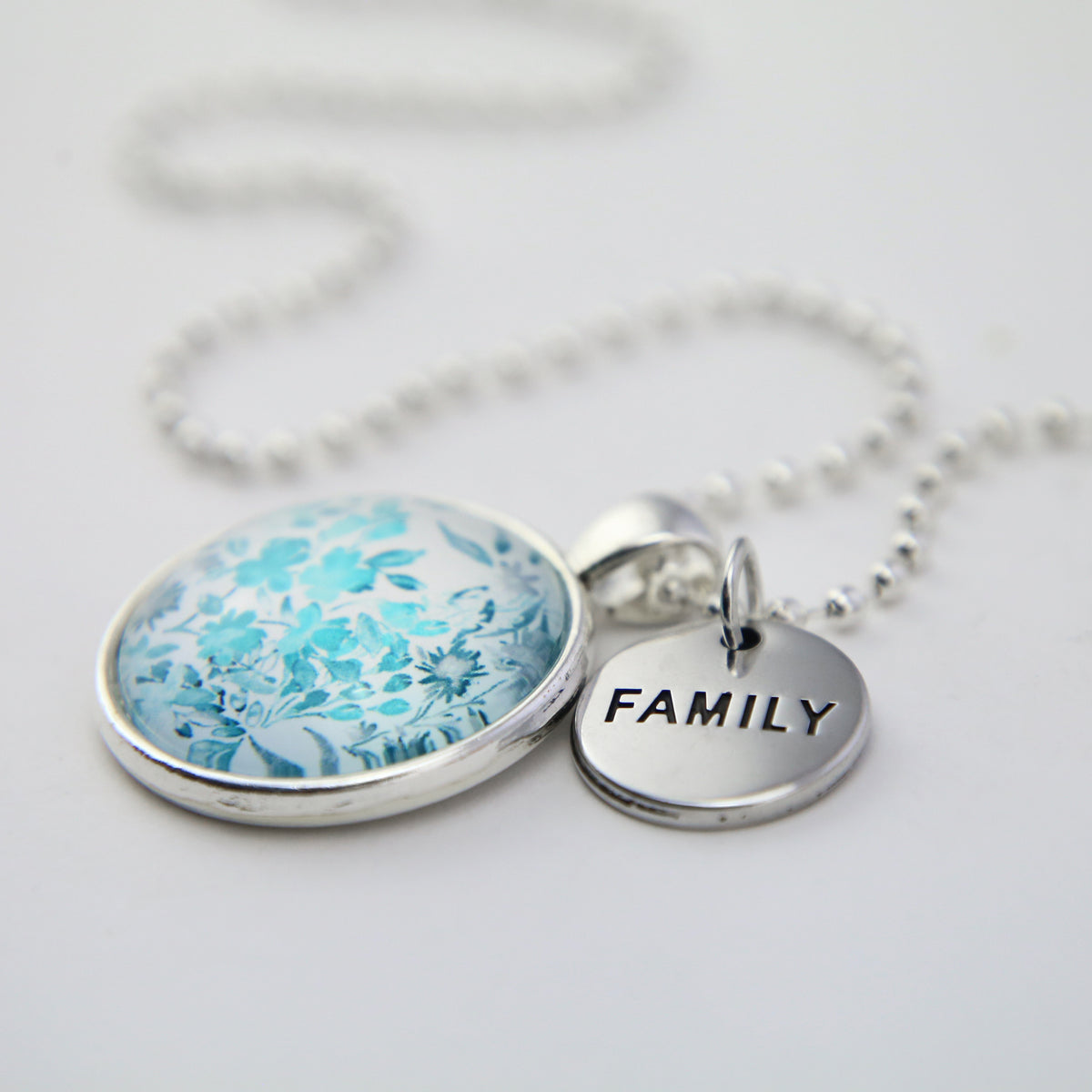 Teal print floral pendant necklace in bright silver with family charm. 