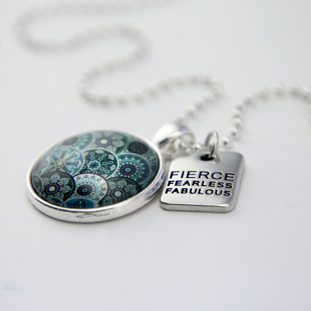 Teal print mandala pendant necklace in bright silver with fierce fearless fabulous charm. 