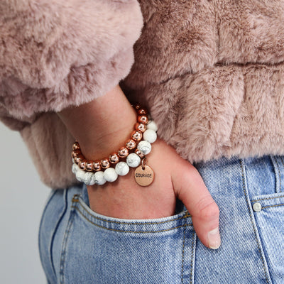 Girl wearing white marble howlite bead braclet with rose gold clip and courage charm with rose gold stacker bracelet. Bracelet Duo set.