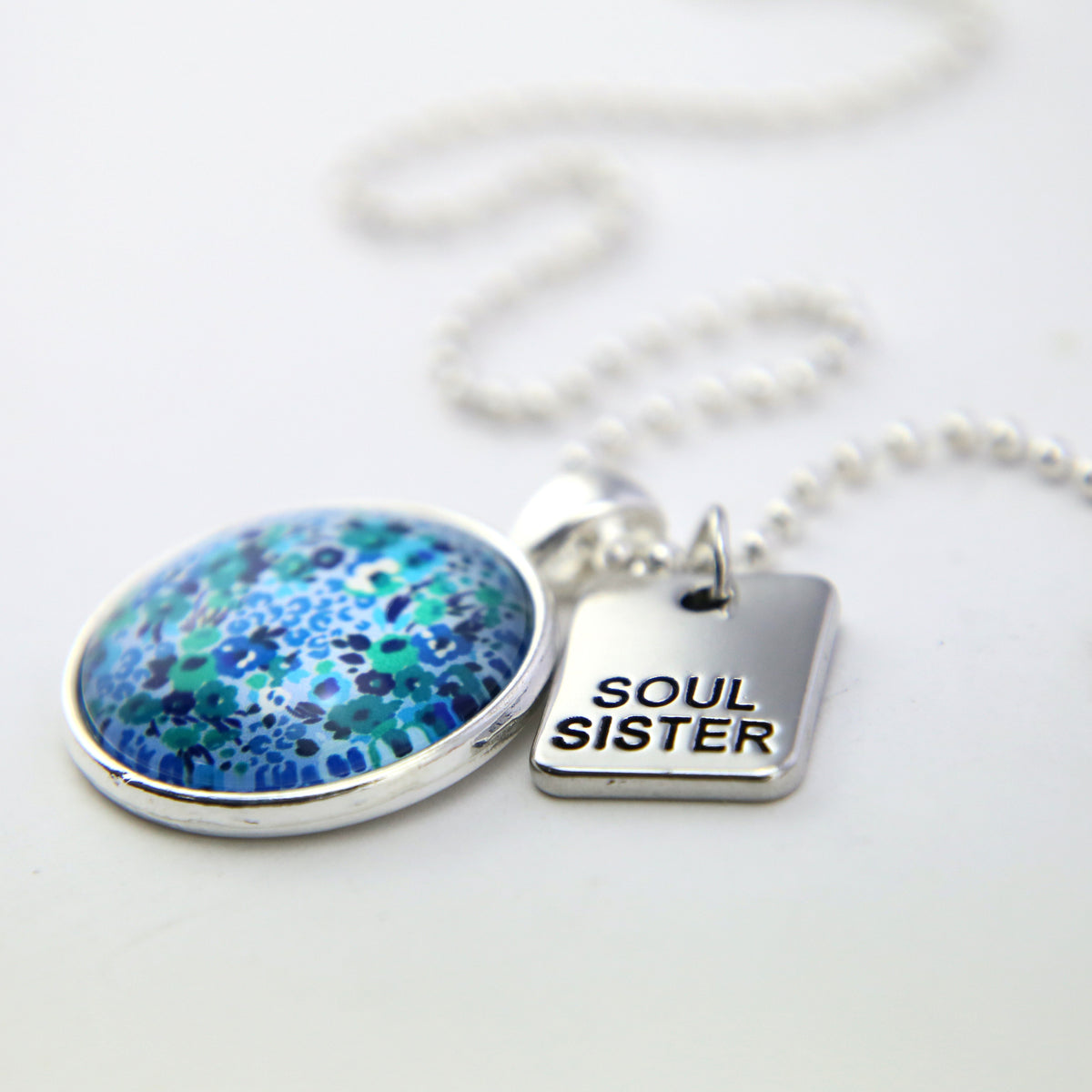 Teal floral print pendant necklace in bright silver with soul sister charm. 